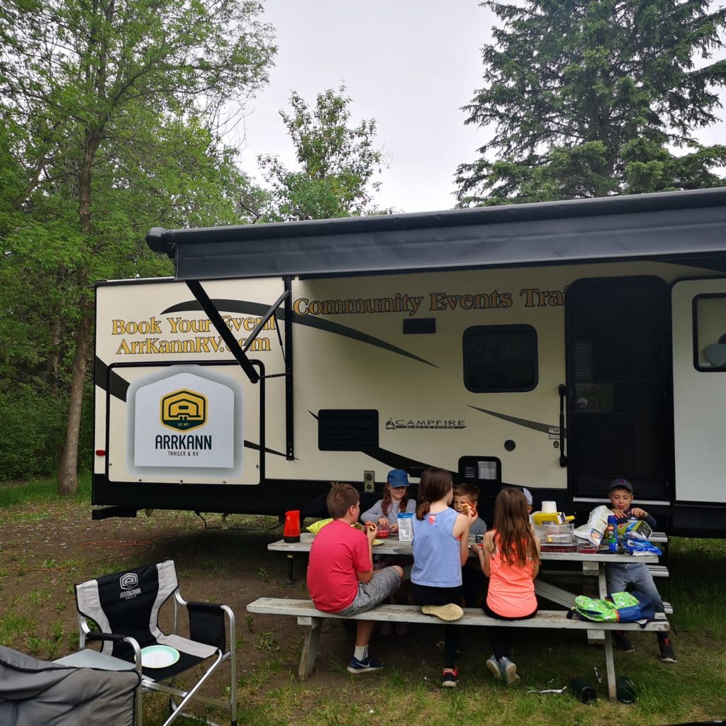 Kids sitting around a picnic bench at Rainbow Valley campground