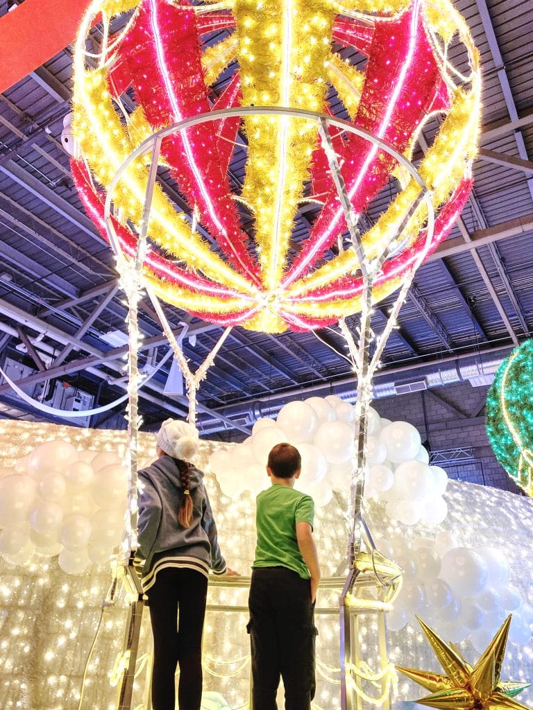 Children in a faux hot air balloon made of Christmas lights at GLOW Edmonton.