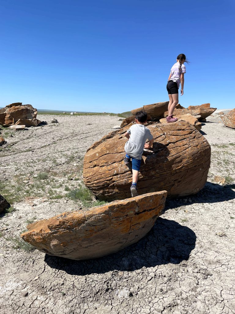 Kids climbing on the round iron rocks of Red Rock Coulee