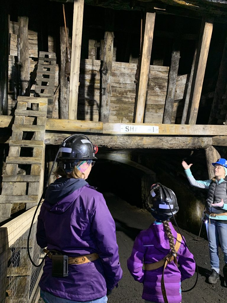 Mom and daughter listen to presentation by female guide in Bellevue Underground Mine.